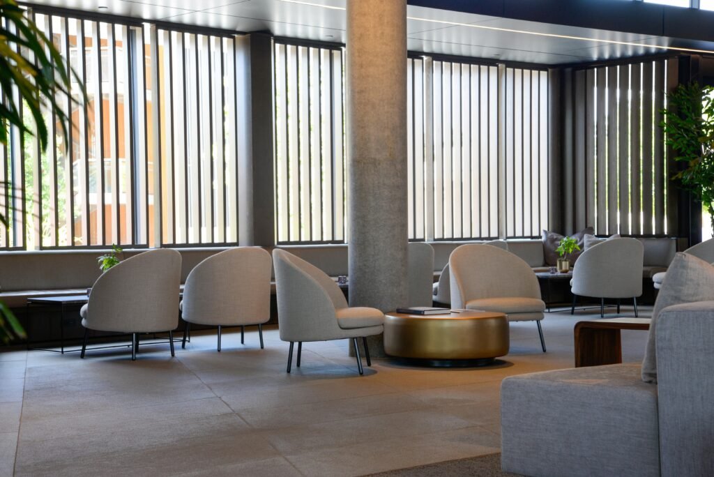 Spacious hotel lounge with stylish chairs and tables, featuring natural light and modern design elements.