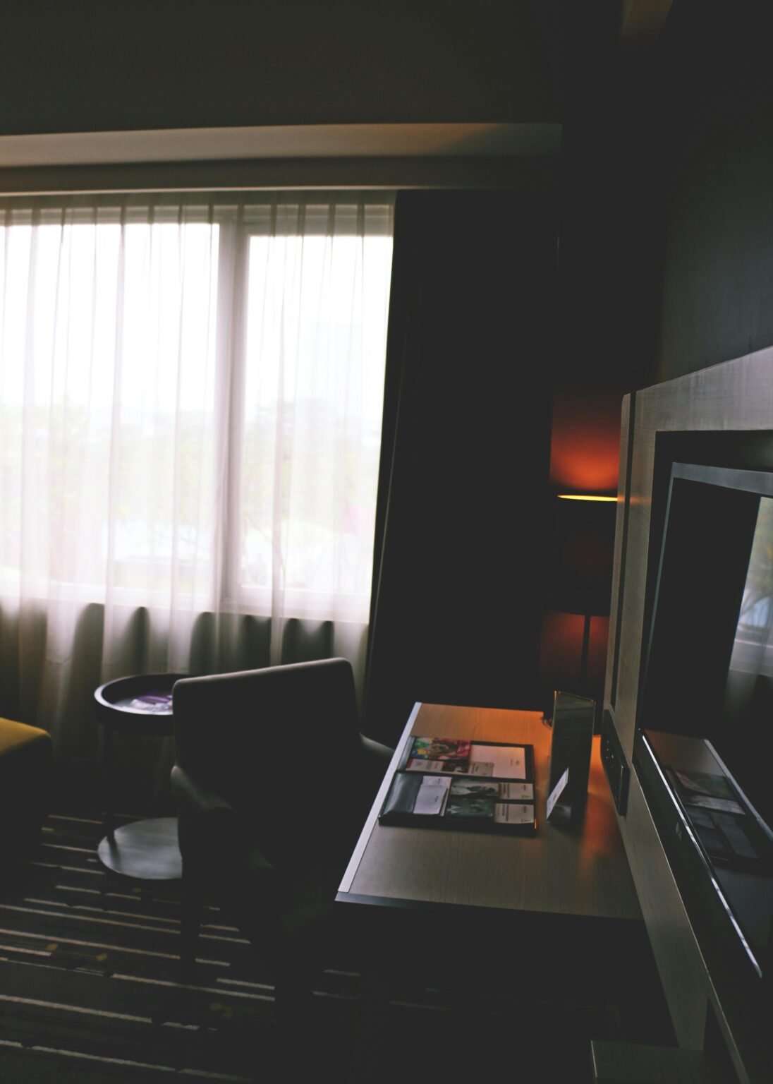 Luxurious hotel room featuring modern interior design with desk and large window for natural light.