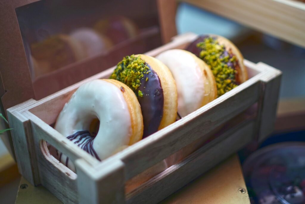 A close-up of delicious assorted donuts with various toppings presented in a rustic wooden box.