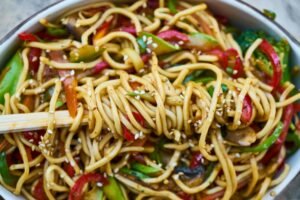 Vibrant stir-fried vegan noodles with colorful vegetables and sesame seeds.