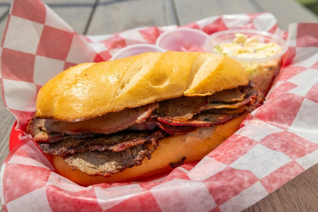 Mouthwatering brisket sandwich served in a red checkered basket with coleslaw on the side.