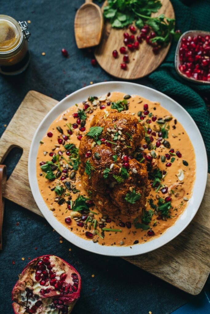 Delicious roasted cauliflower with vibrant garnet sauce and garnished with herbs, perfect for a healthy vegan meal.